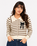 Woman wearing a cream and brown striped knit cardigan with pearl buttons and a black bow brooch